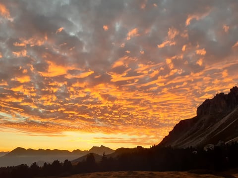 Dramatic sunset sky with golden and orange clouds above silhouetted mountains and rock formations